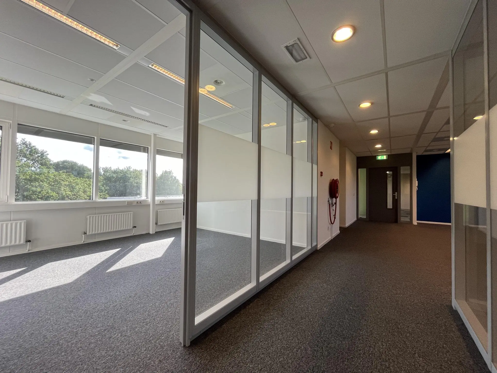 Lichte kantoorruimte aan de Baarnsche Dijk met grote ramen en glazen scheidingswanden.